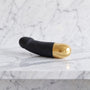 Korte zwarte vibrator met gouden onderkant op een marmeren plank, Dorcel Real Vibration S