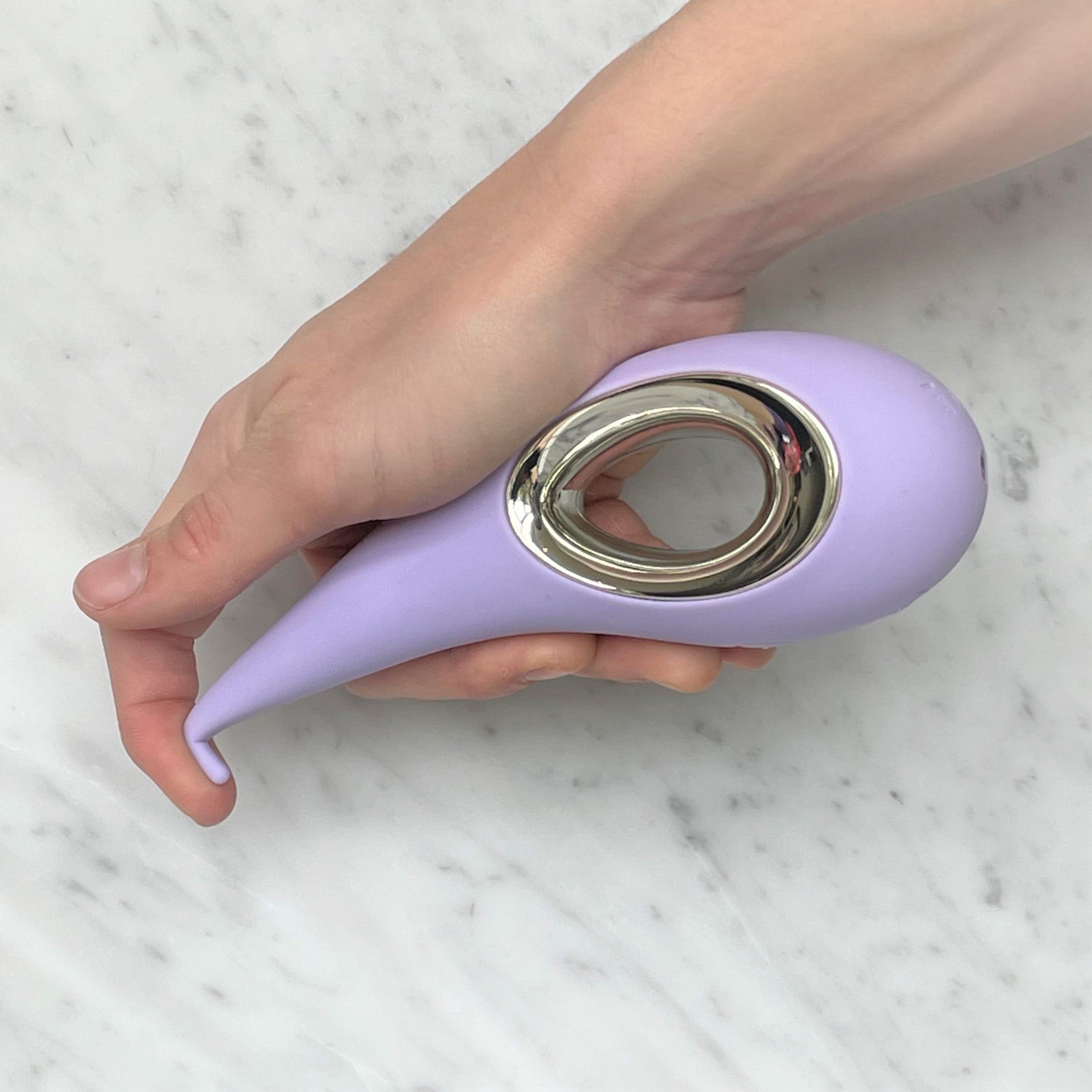Hand buigt het smalle puntje van de lila clitorisvibrator, LELO Dot in lavendel