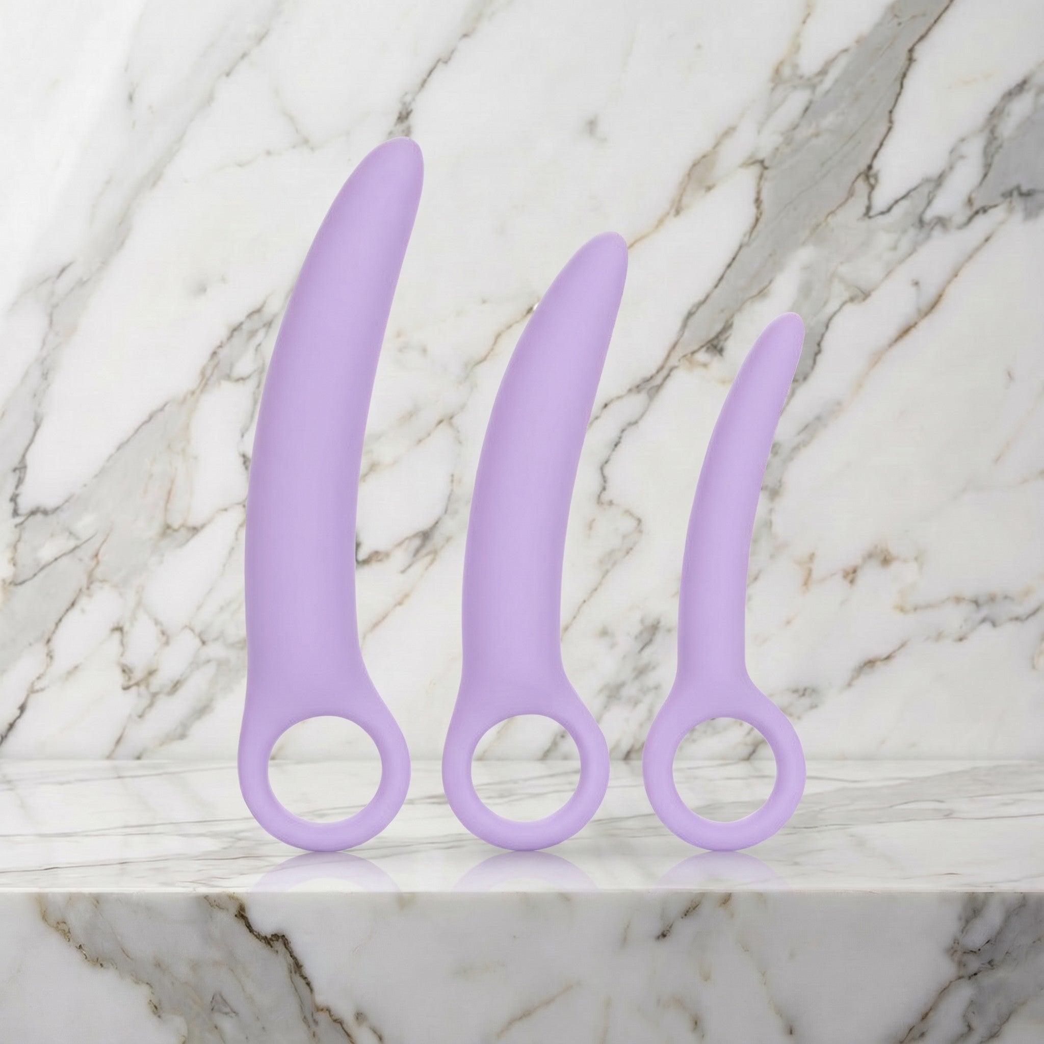 Drie lila siliconen dilators met ring als handvat rechtop op een marmeren plank, dilatorset van Dr. Berman