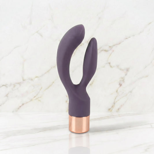Slanke donkerpaarse rabbit vibrator met rose gouden kap op een marmeren plank, Elegant