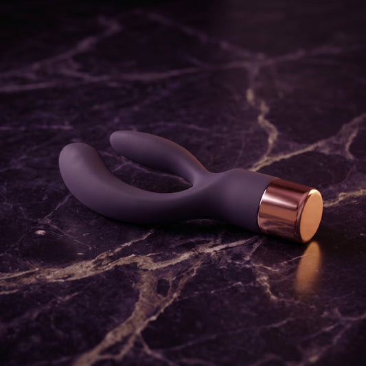 Sfeerbeeld: donkerpaarse rabbit vibrator Elegant liggend op donkerpaars marmer in gedempt licht