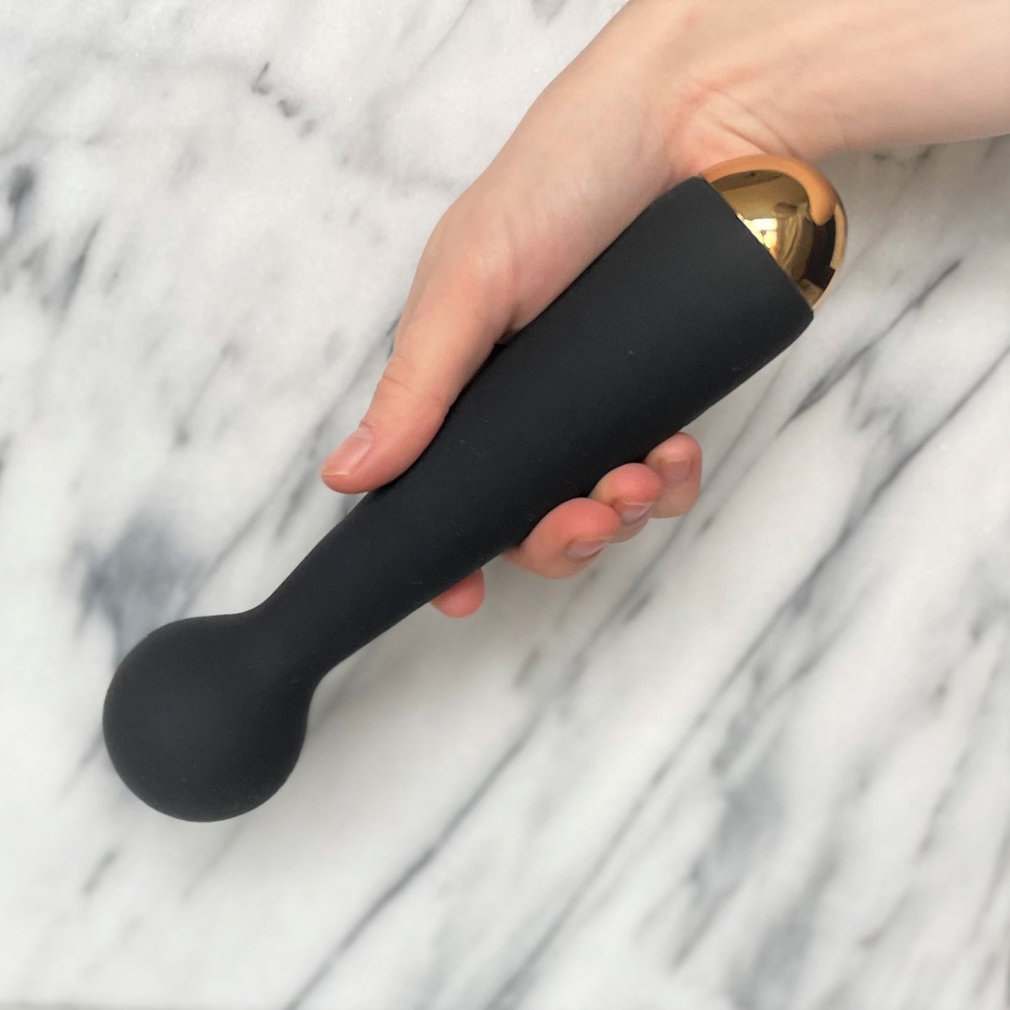 Emma Neo Wand vibrator vastgehouden in hand, slank zwart ontwerp met gouden accent