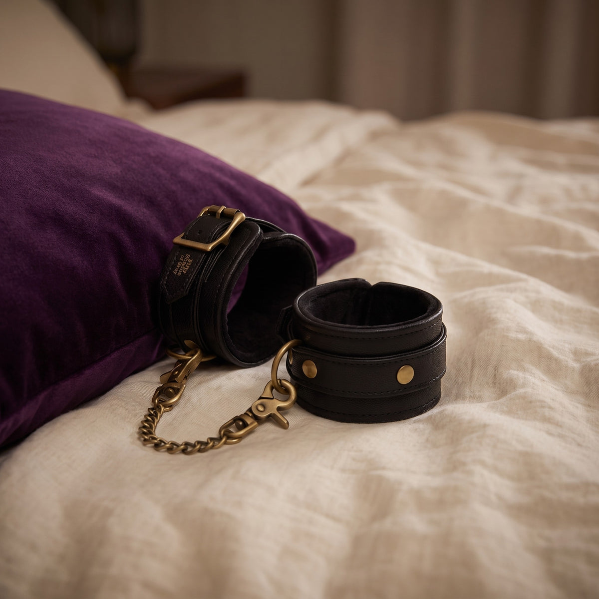 Sfeerbeeld: de enkelboeien op creme linnen naast een paars kussen, Fifty Shades of Grey