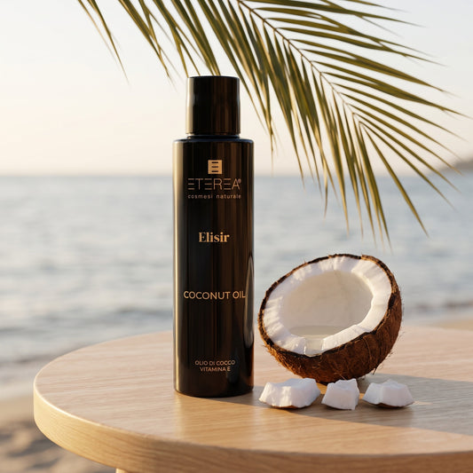 Sfeerbeeld: fles Eterea Coconut Oil op een houten tafel met een halve kokosnoot en een palmblad aan zee