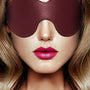 Model draagt bordeauxrode leren blinddoek op gezicht, BDSM oogmasker van zacht leer