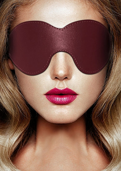 Model draagt bordeauxrode leren blinddoek op gezicht, BDSM oogmasker van zacht leer