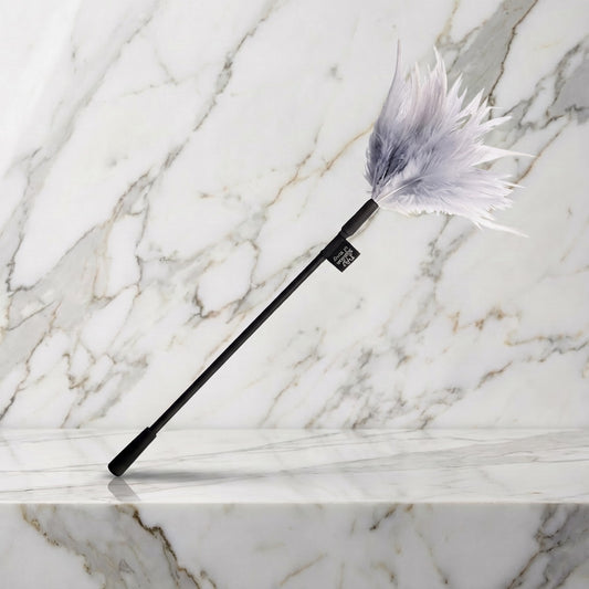Fifty Shades Tease streelveer met lichtgrijze veren en zwarte steel op een marmeren plank