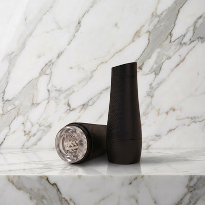 Zwarte Fleshlight Flight Pilot koker rechtop op een marmeren plank met de losse doorzichtige huls ernaast
