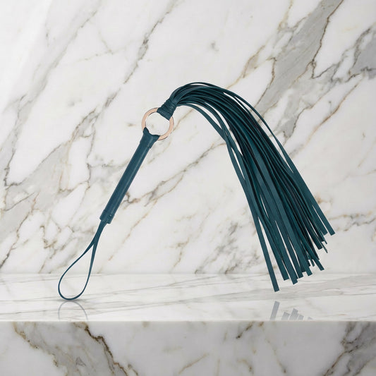 Groene flogger met 30 strengen en goudkleurige ring op een marmeren plank