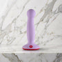 Lila Fun Factory Amor dildo met rode zuigvoet rechtop op een marmeren plank