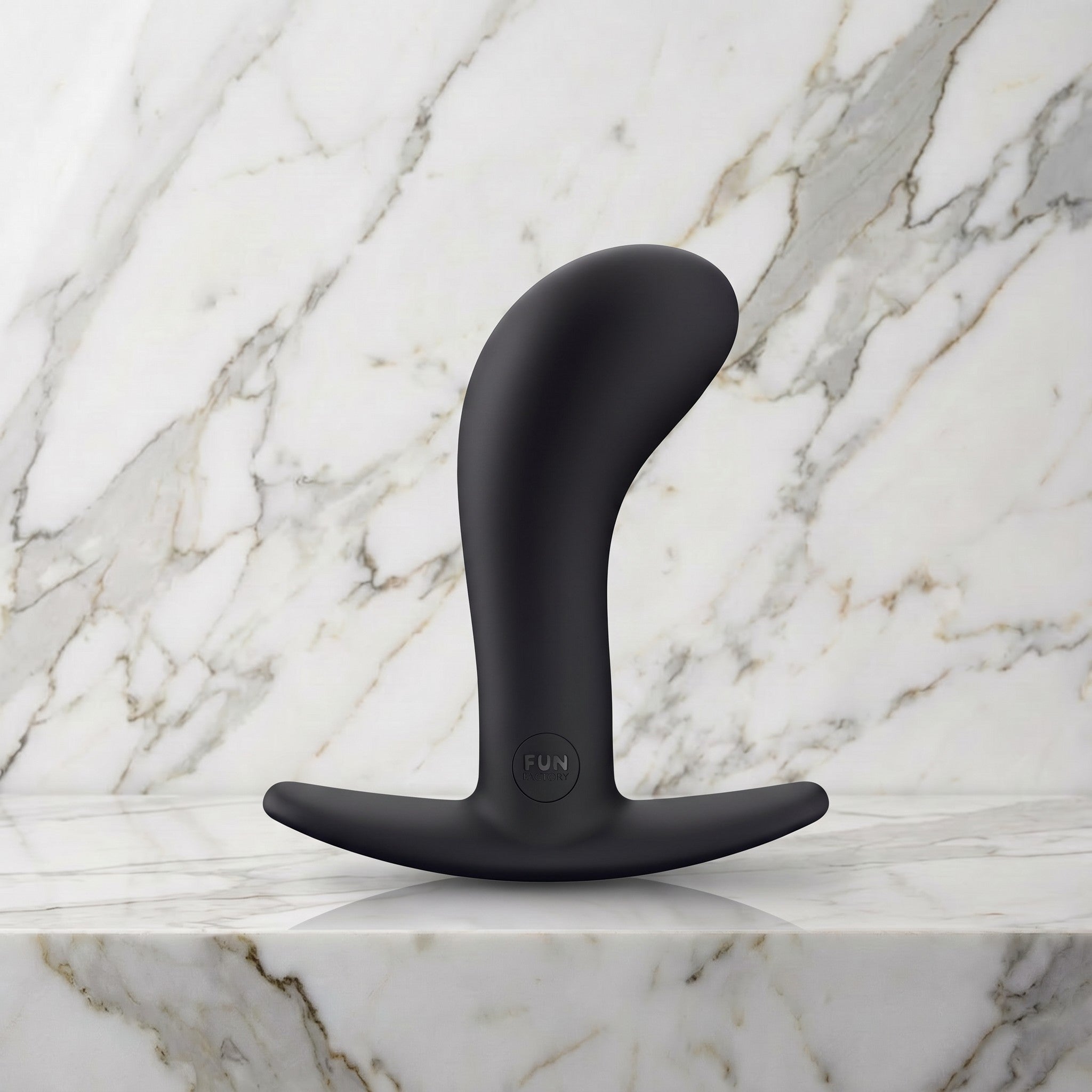 Zwarte gebogen buttplug Bootie Large met T-voet op een marmeren plank, Fun Factory