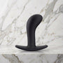 Zwarte gebogen buttplug Bootie Large met T-voet op een marmeren plank, Fun Factory