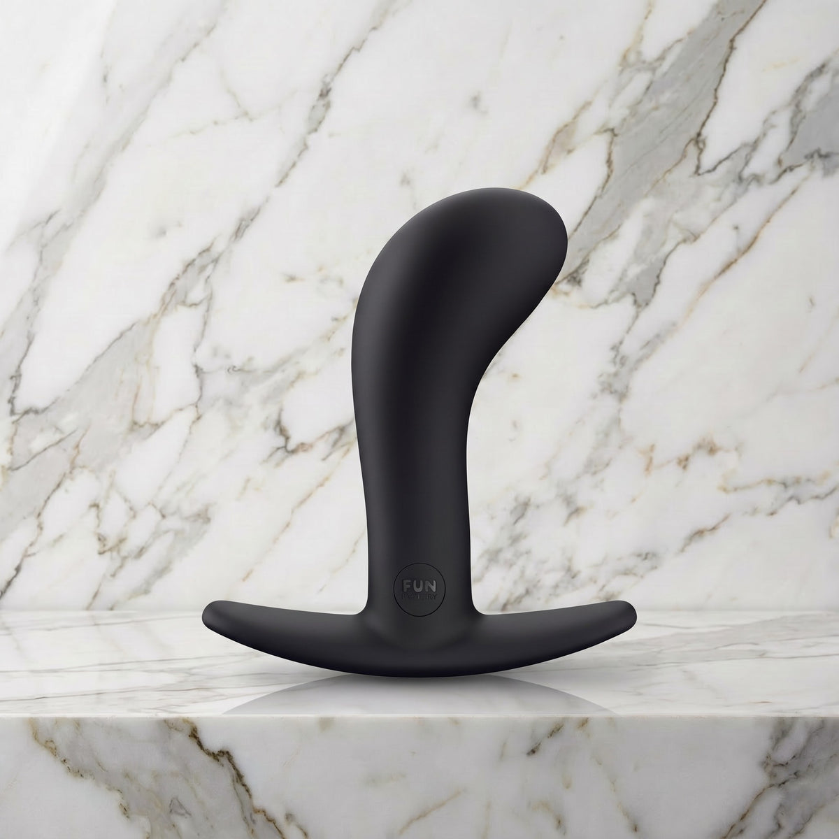 Zwarte gebogen buttplug Bootie Large met T-voet op een marmeren plank, Fun Factory