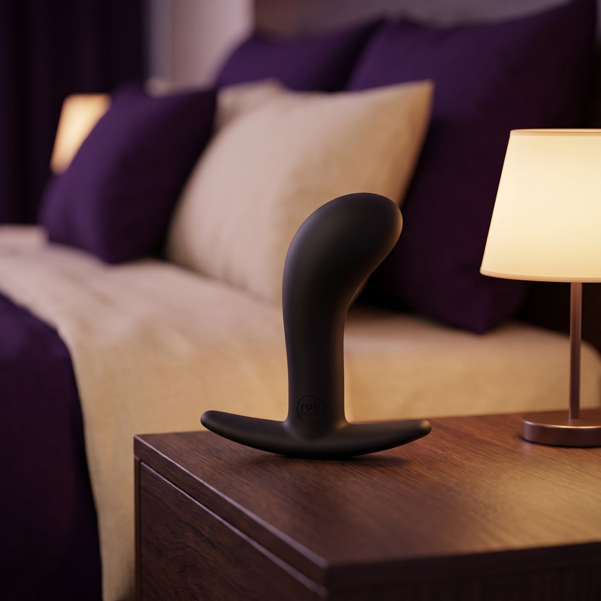 Sfeerbeeld: zwarte Bootie Large buttplug op een nachtkastje naast een lampje