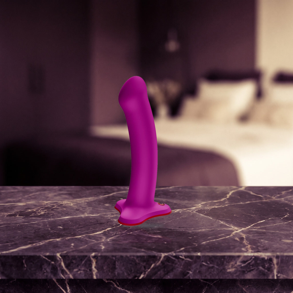 Sfeerbeeld: roze MAGNUM dildo rechtop op een donker marmeren nachtkastje bij lamplicht