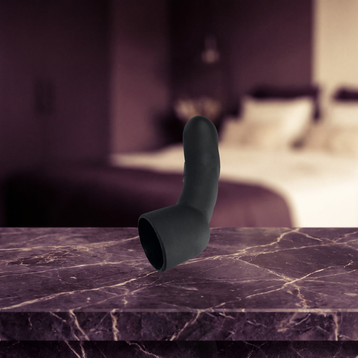 Sfeerbeeld: zwart G-spot opzetstuk op donkerpaars marmer in een slaapkamer