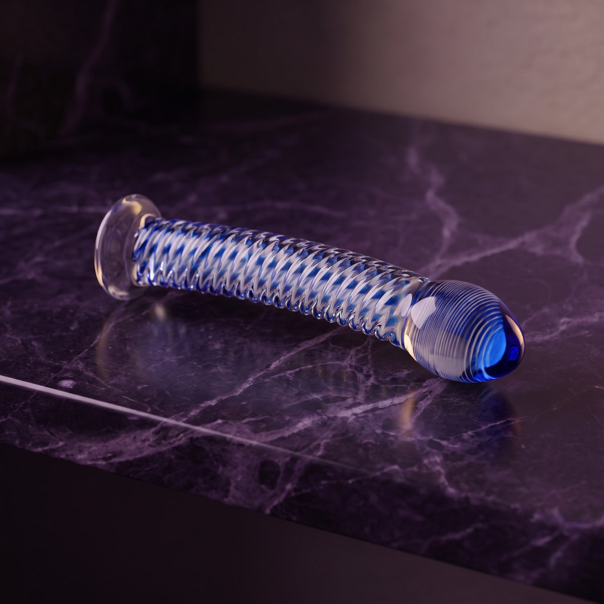 Sfeerbeeld: glazen dildo Gildo No. 5 met blauwe spiraal op donkerpaars marmer