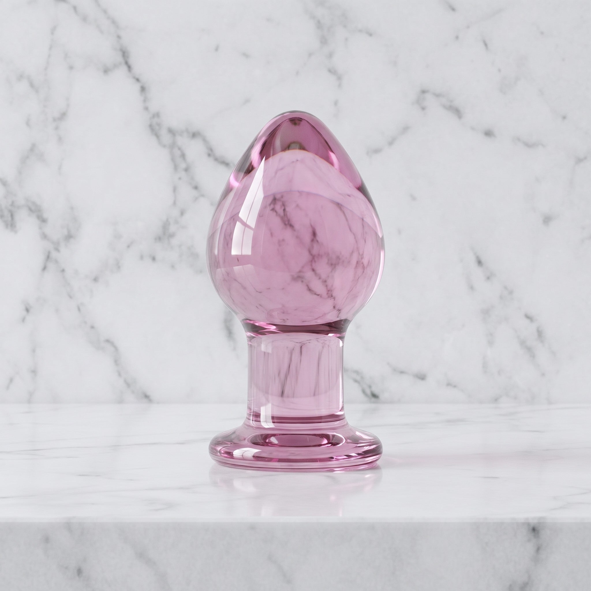 Roze doorzichtige glazen buttplug rechtop op een marmeren plank, van Gildo