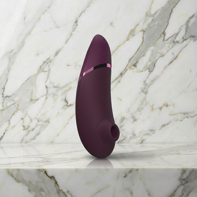 Paarse Womanizer Next staand op een marmeren plank, luchtdrukvibrator van Womanizer