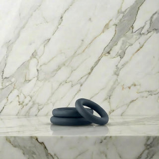 All-round Cockring Set: drie donkergrijze siliconen cockringen op een marmeren plank