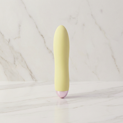 Lichtgele Cuties mini vibrator rechtop op een marmeren plank
