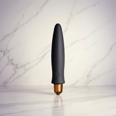 Zwarte Slinky vibrator met koperen bullet rechtop op een witte marmeren plank, Rocks-Off