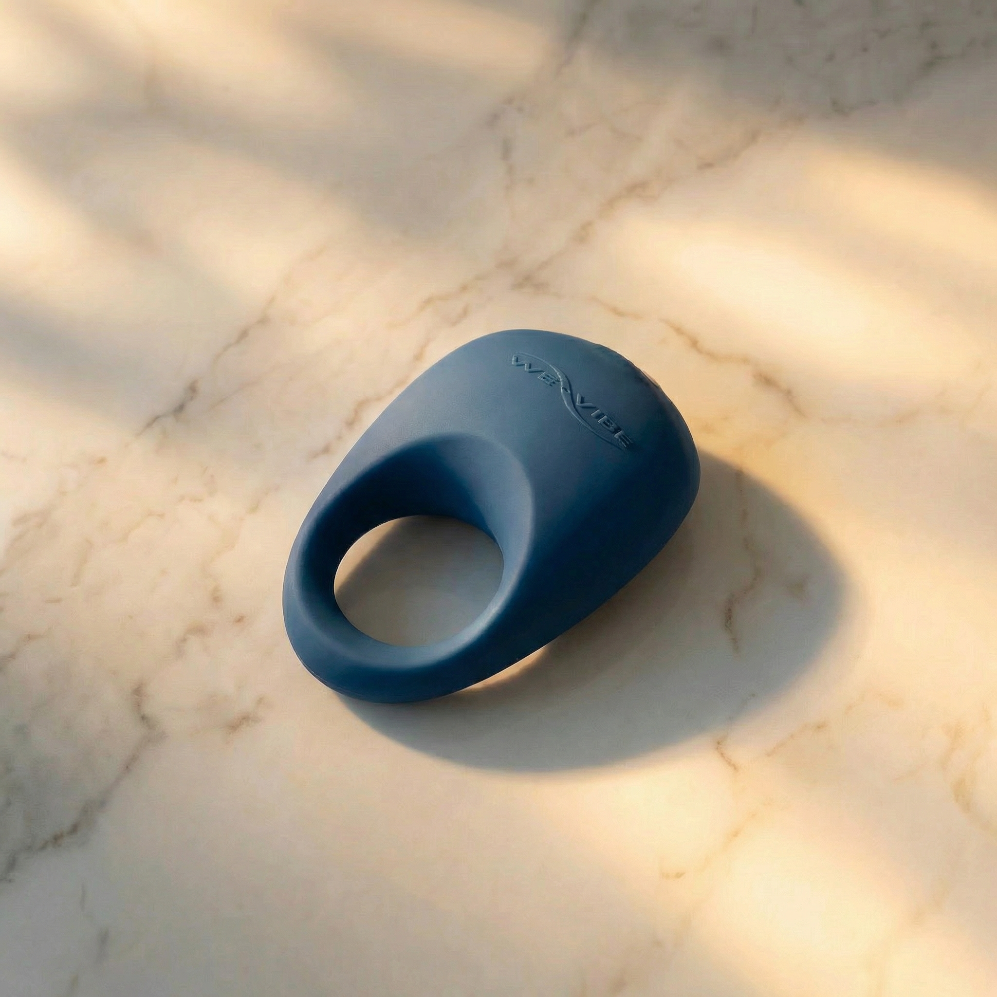 Donkerblauwe We-Vibe Pivot vibrerende cockring op een marmeren plank