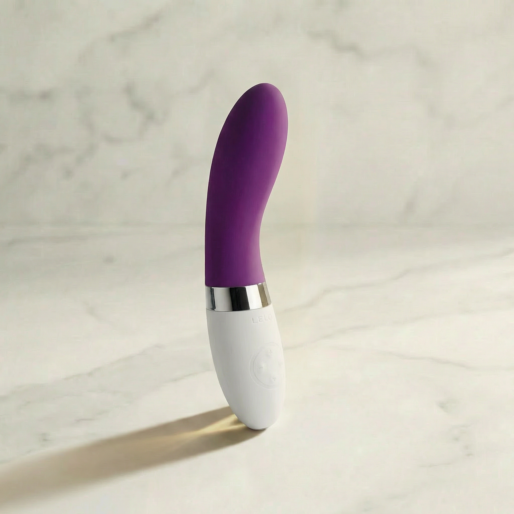 Paarse Lelo Liv 2 staafvibrator met wit handvat rechtop op een marmeren plank