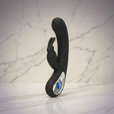Zwarte Black and Pink Beauty rabbit vibrator met oortjes en ring rechtop op een marmeren plank