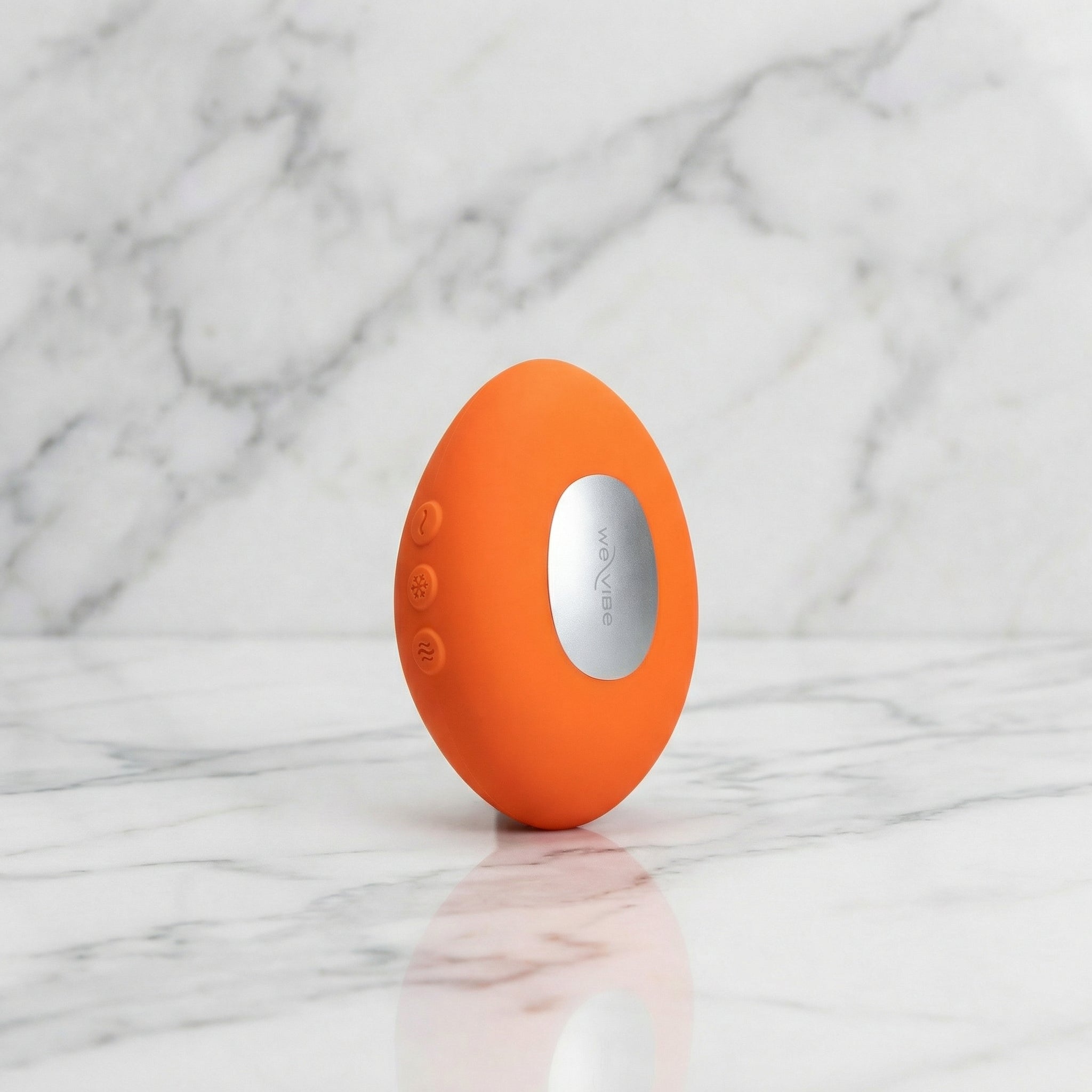 Oranje We-Vibe Temp oplegvibrator rechtop op een marmeren plank