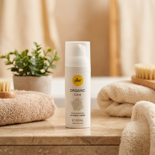 Pjur Organic Care pompflacon in badkamersetting met beige handdoeken, houten borstel en groen plantje