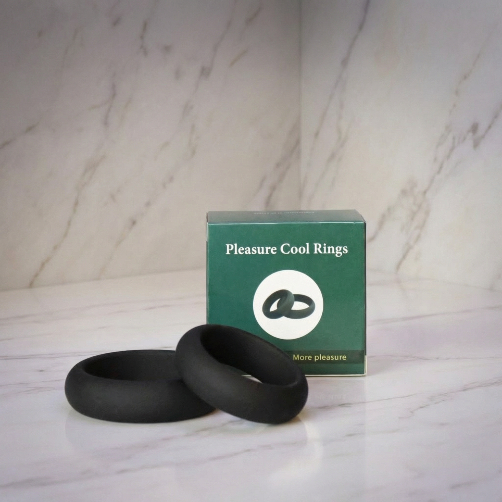 Twee zwarte cockringen voor het groene doosje op een marmeren plank, Pleasure Cool Cockringen set