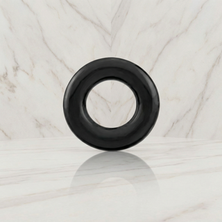 Zwarte cockring rechtop op een marmeren plank tegen een marmeren wand, Kleine cockring