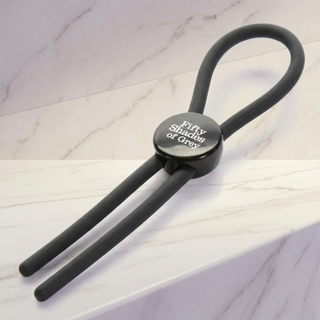Verstelbare lasso cockring van Fifty Shades of Grey in zwart siliconen op een marmeren plank