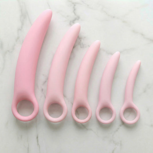 Vijf roze siliconen dilators in oplopende maten met ringetjes bovenaanzicht