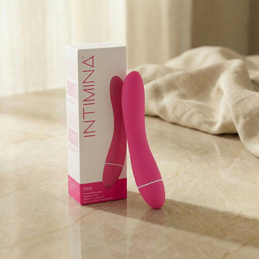 Roze Intimina Raya persoonlijke massager naast wit-roze verpakking op marmeren ondergrond