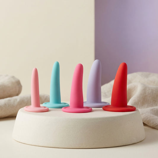 Vijfdelige siliconen dilatorenset in pastelkleuren op podium, oplopende maten voor vaginale training