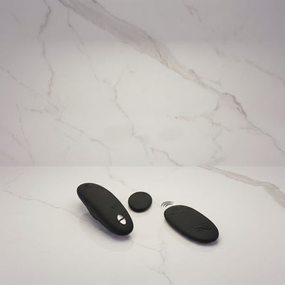 Zwarte We-Vibe Moxie+ met magneet en afstandsbediening op een marmeren plank