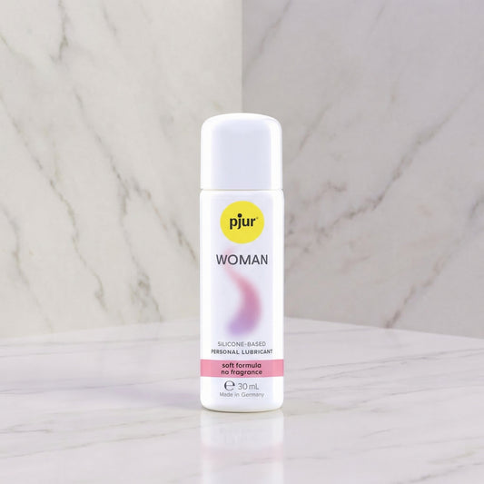Pjur Woman siliconen glijmiddel 30 ml, witte fles met roze accent, op marmeren achtergrond