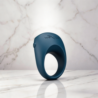 Donkerblauwe We-Vibe Pivot 2 penisring rechtop op een marmeren plank