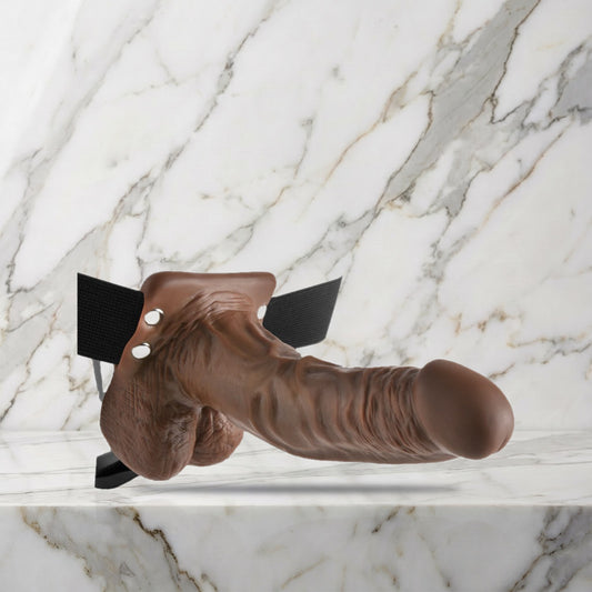 Bruine holle strap-on met balzak en zwarte heupband op een marmeren plank
