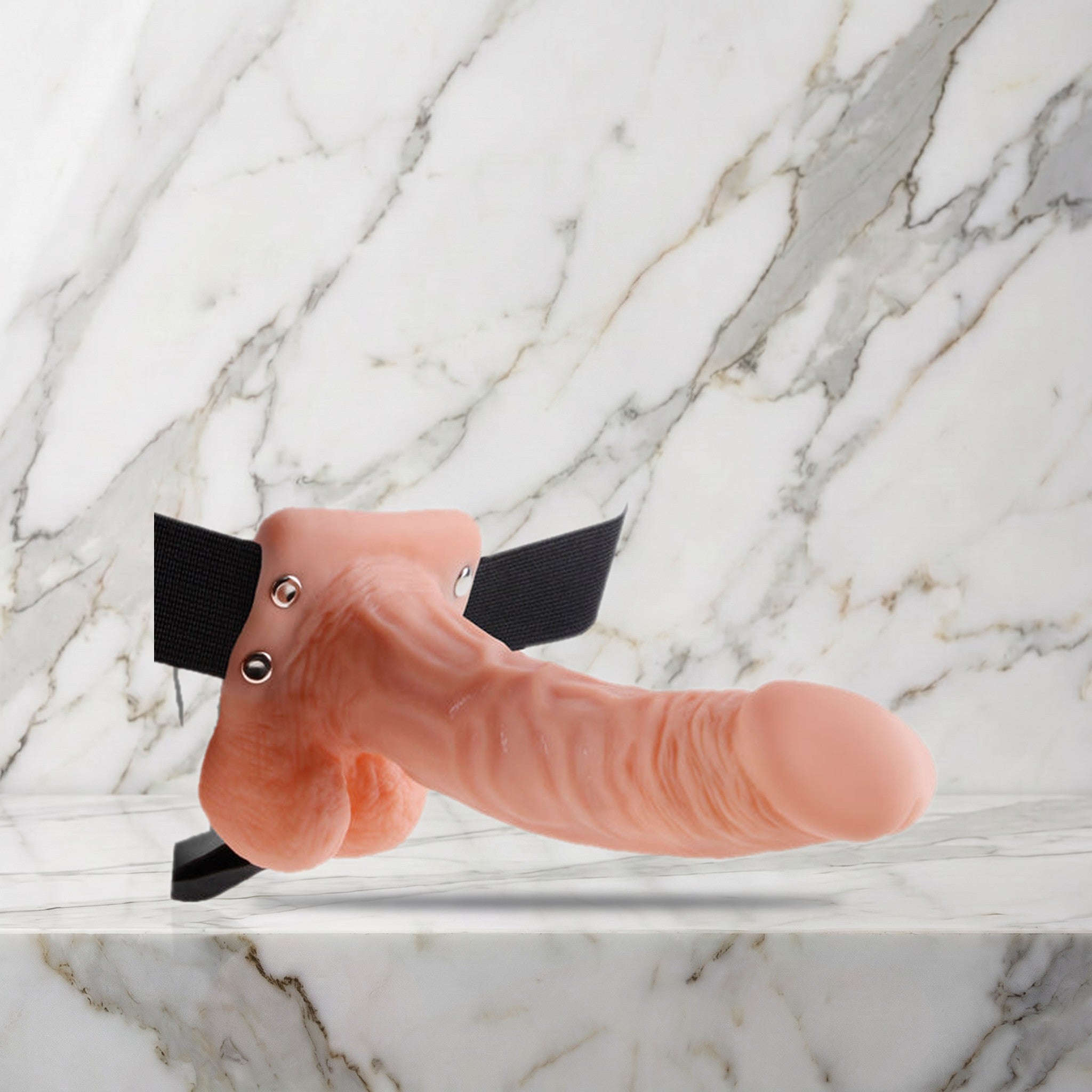Nude holle strap-on met balzak en zwarte heupband op een marmeren plank