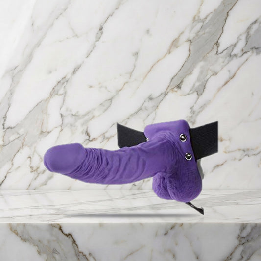 Paarse holle strap-on met balzak en zwarte heupband op een marmeren plank