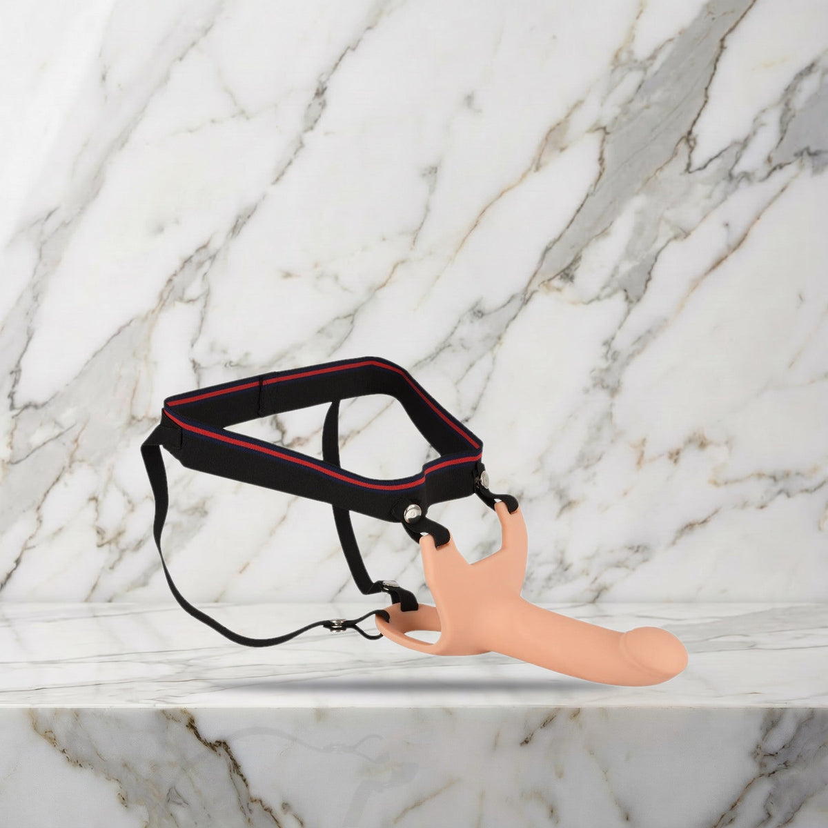Nude holle strap-on van siliconen met zwart harnas op een marmeren plank, maat S/M