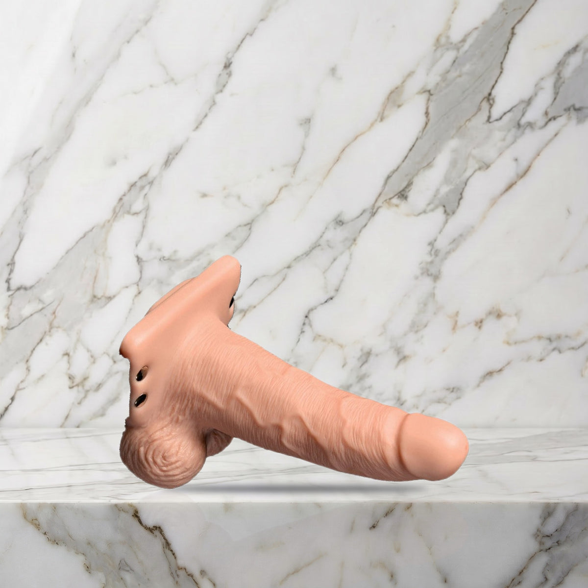 Nude holle strap-on met vibratie liggend op een marmeren plank, maat S