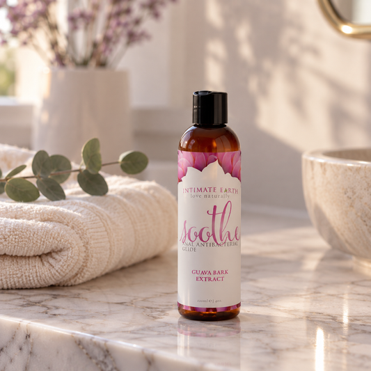 Fles Intimate Earth Soothe op een marmeren badkamerblad naast een handdoek en eucalyptus