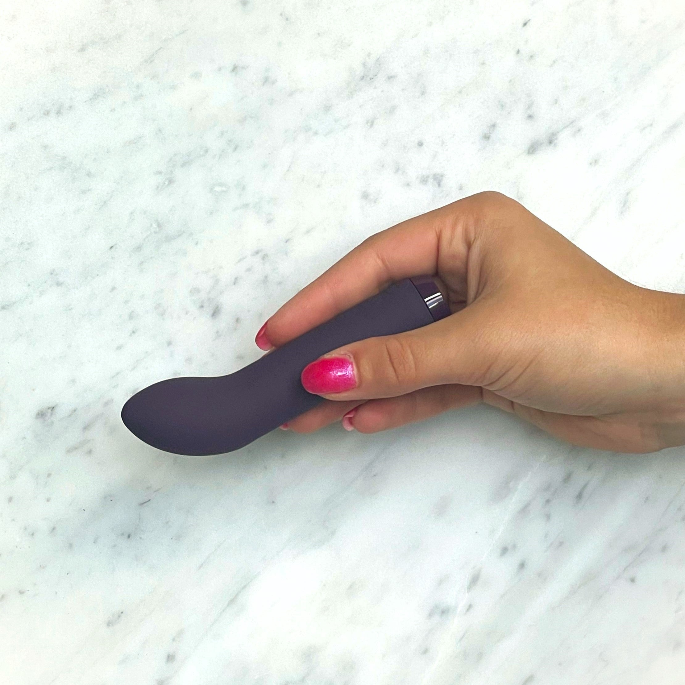 Paarse mini vibrator in een hand op marmer, zo ziet u het kleine formaat