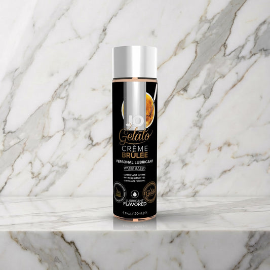 Zwarte fles JO Gelato Crème Brûlée glijmiddel met zilveren dop op een marmeren plank