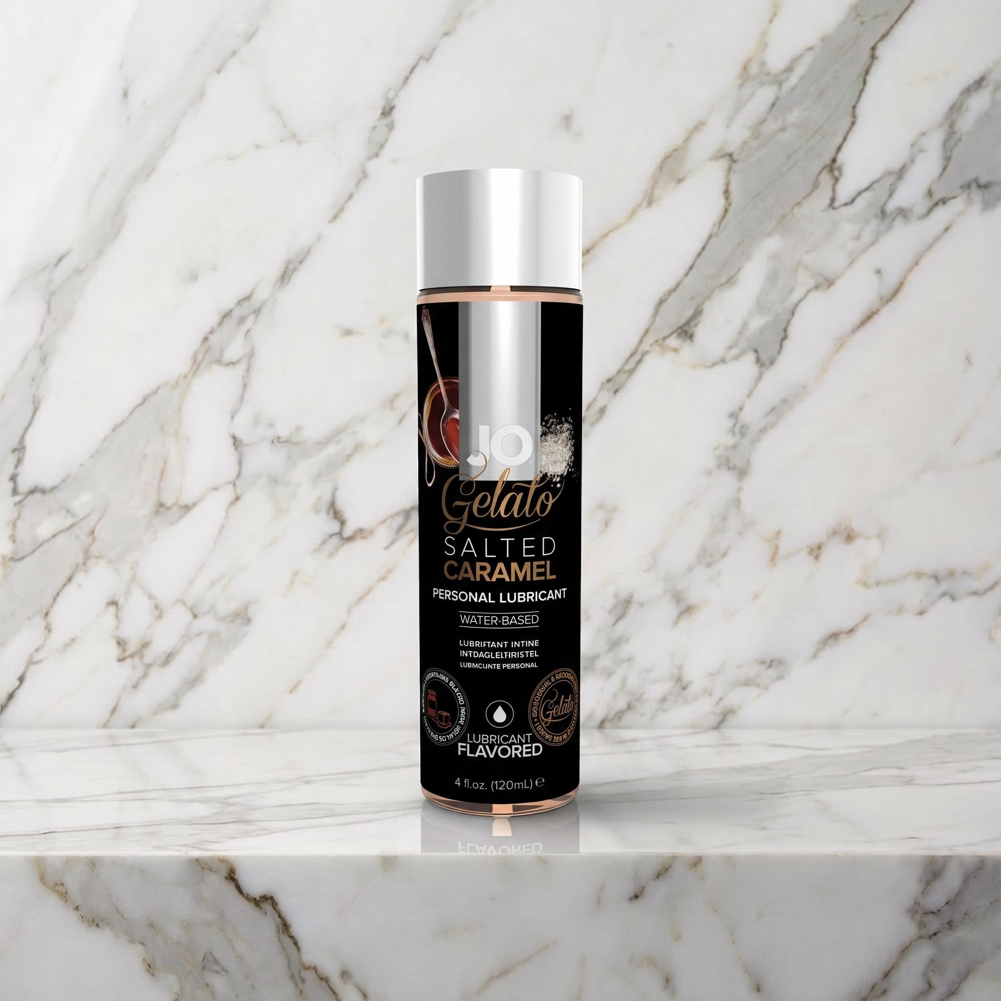 Zwarte fles JO Gelato Salted Caramel glijmiddel met zilveren dop op een marmeren plank