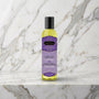 Fles Harmony Blend massageolie met paars etiket op een marmeren plank, Kama Sutra